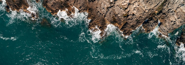 Top view of the sea waves hitting the rocks