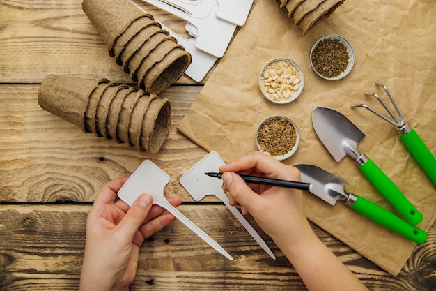 Top view of seeds and garden tools on a wooden background Womens hands sign a sign for the plant