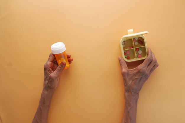 Top view of senior women holding medical pill container and pill box