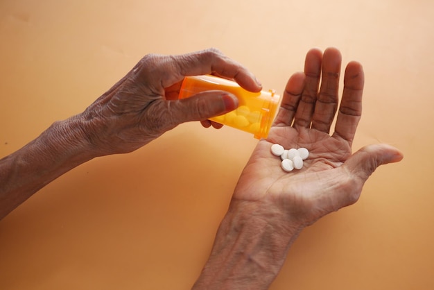 Top view of senior women taking pills on orange background