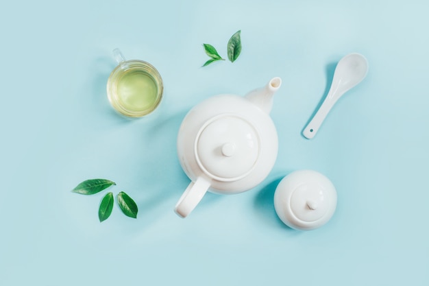 Top view of a set of tea utensils teapot sugar bowl cup with tea on a blue background