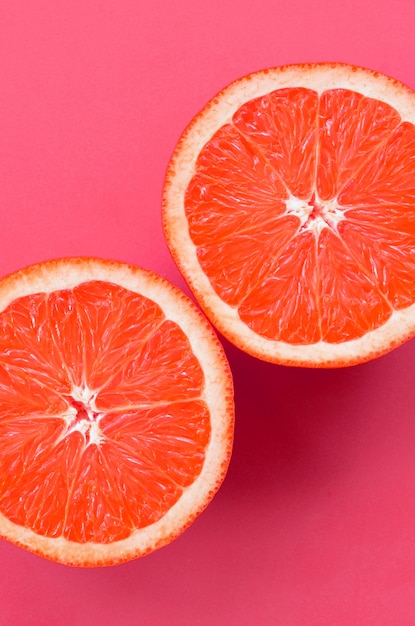 Top view of a several grapefruit slices on bright pink 