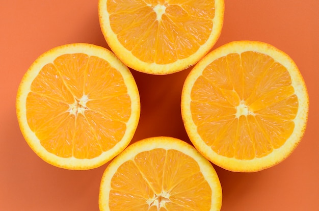 Top view of a several orange fruit slices on bright background in orange color