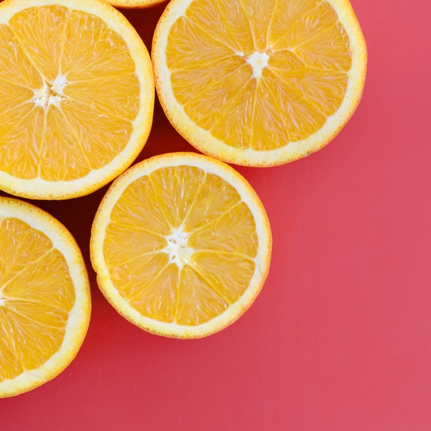 Top view of a several orange fruit slices on bright background in red color. A saturated citrus texture image