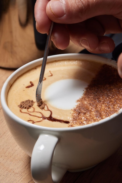 Top view shot of professional barista pouring milk from jar in to a cup of coffee coffee being prepa