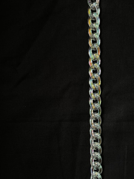 Top view shot of trnasparent irridescent plastic chain on black background