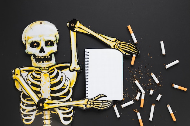 Photo top view skeleton with cigarettes and notebook