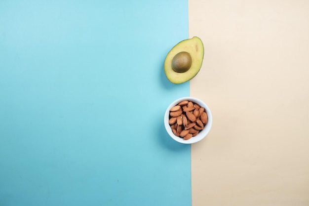 Top view of slice of avocado and almond nuts on color background