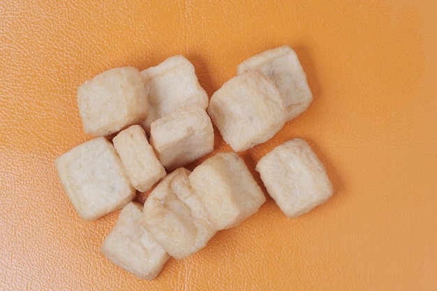 Top view of slice of Tofu on orange background