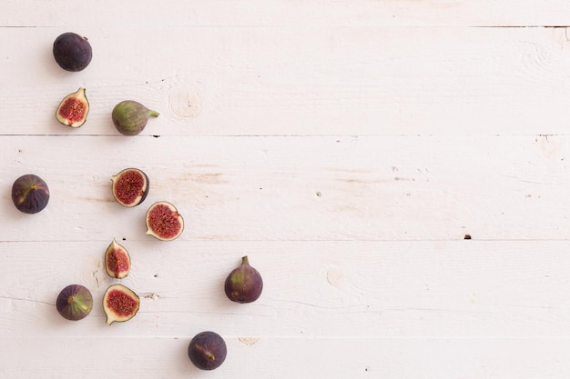 Top view on sliced and full fresh figs on white wooden table or background