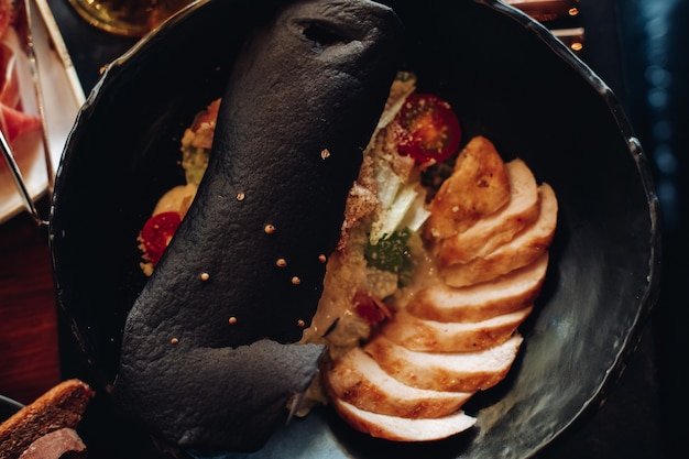 Top view of a sliced meat with warm vegetable salad and a big piece of bread on the top. Food concept