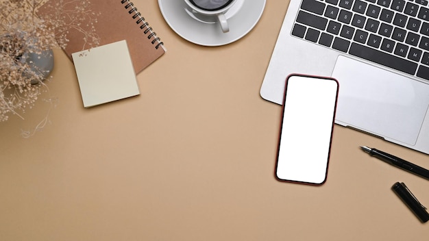 Top view smart phone laptop computer and notebook on beige background