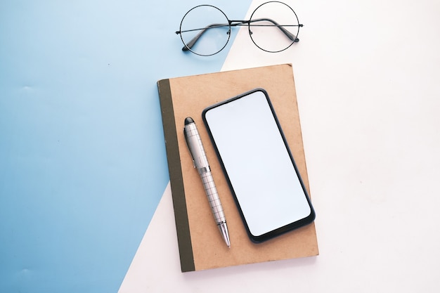 Top view of smart phone and notepad on table