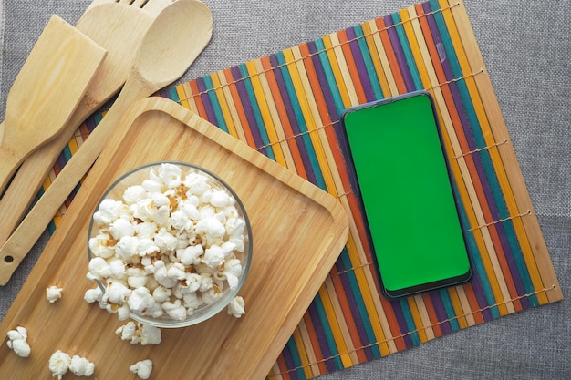 Top view of smart phone and popcorn on table