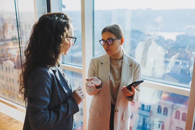 Photo top view of smiling young confident business workers in casual clothes standing on modern office background and talking during day break