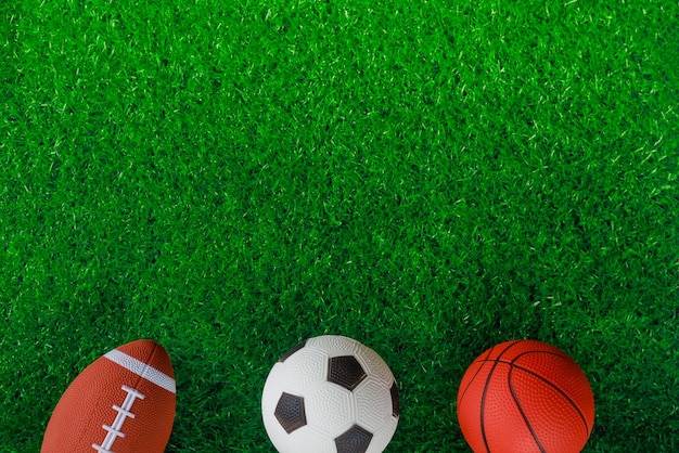 Top view of soccer basketball and football balls on green background