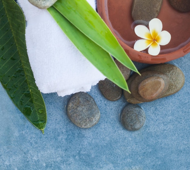 Top view of spa flower and stones towel leaves for relax massage treatment on marble background