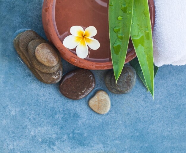 Top view of spa objects and stones for massage treatment on blue table background