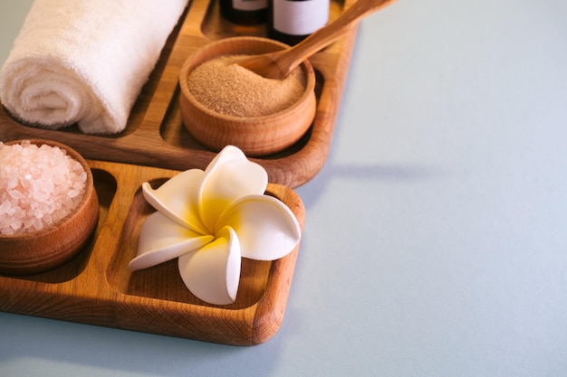 Top view spa set oils sea salt and clay scrub on a wooden tray Selfcare conceptBlue background Copy space