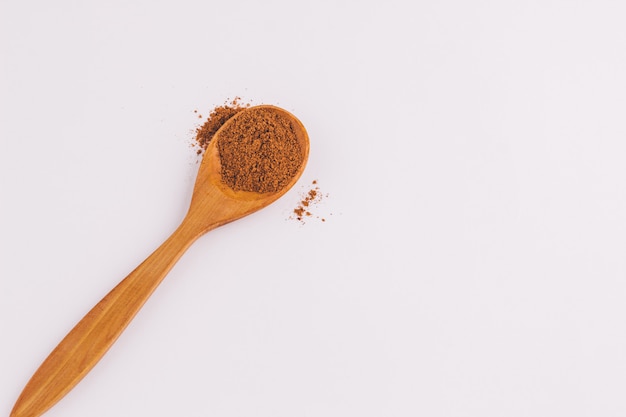 Top view of a spoon of sandal wood with cinnamon on light background