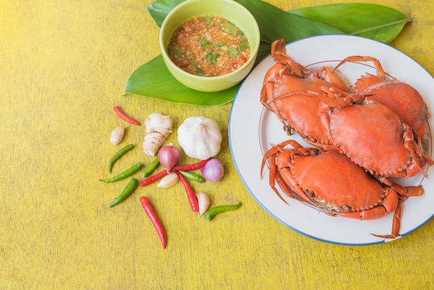 Top view of steamed crap set with seafood sauce on yellow wooden  table