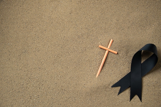 Top view of stick cross with black bow on the sand