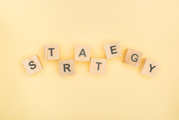 Top view of strategy lettering made of wooden blocks on yellow background