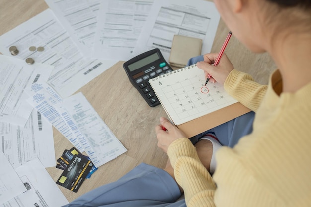 Top view stressed asian woman girl owe mortgage sitting on floor at home calculate expense from bills no money to pay in mark circle deadline on calendar Debt bankrupt people concept