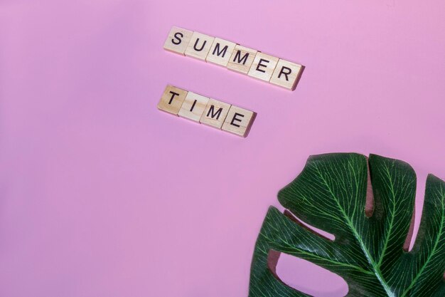 Top view summer time lettering of alphabet wooden blocks on pink background