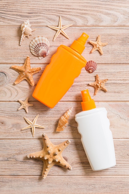 Photo top view of sunscreen bottle with seashells and starfish on wooden board background with copy space. flat lay concept of summer travel vacation