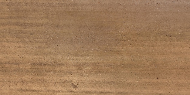 Top view of surface of gravel road made of small stones and sand with traces of car tires