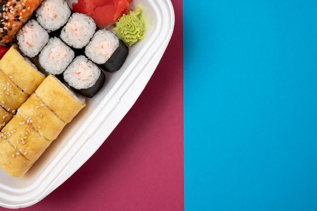 Top view on sushi set at colored background Plate with rolls ginger and vasabi