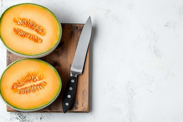 Photo top view of sweet cantaloupe melon with slices on a wooden kitchen board with knife on a white wall