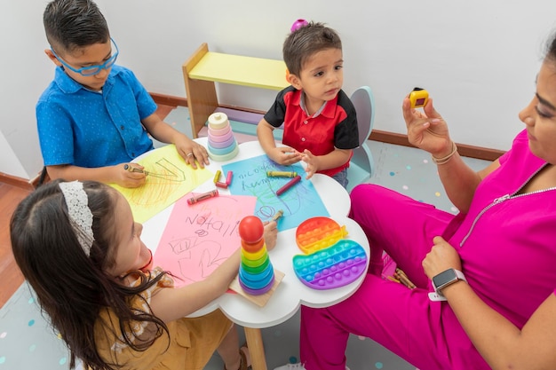 Top view of a table with children and a pediatrician doctor drawing on color sheets with crayons