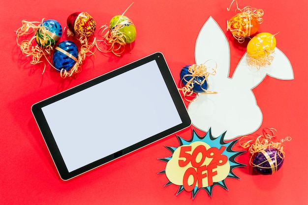 Top view of tablet and easter eggs paper rabbit