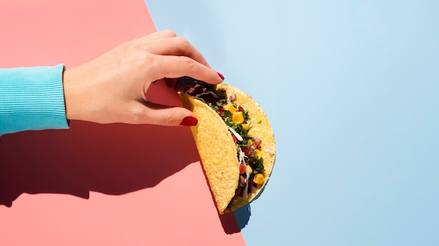 Top view taco with meat and veggies held in hand