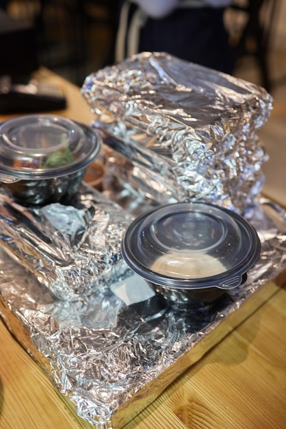 Top view of takeout food in plastic containers and aluminum foil enclosed