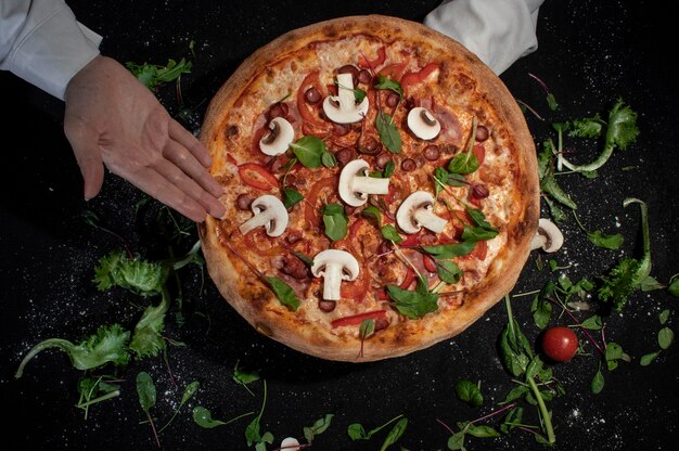 Top view of tasty appetizing classic italian traditional pizza with cheese olives basil and fresh vegetables on dark black table