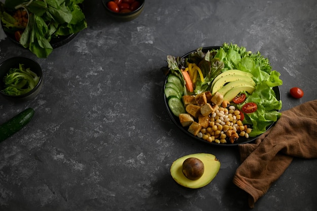 Top view Tasty healthy salad vegetables mixed on a stylish dark background with copy space