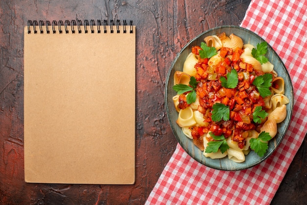 top view tasty pasta with tomato sauce in bowl notebook on wooden table