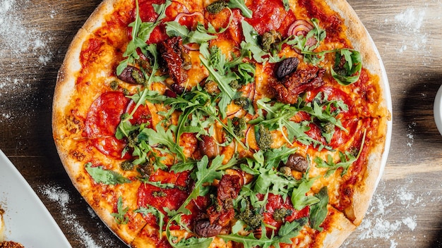 Top view of a tasty pizza with vegetables and greens