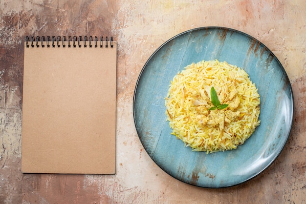 top view tasty plov on round plate notepad on table