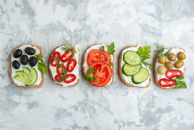 Top view tasty toasts with tomatoes olives and cucumbers on white background sandwich bread food meal dinner burger horizontal