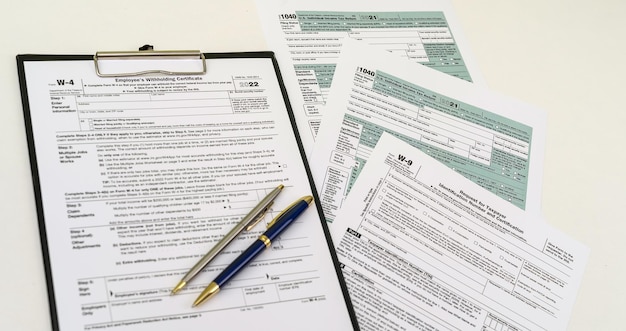 Top view of tax forms on tablet on office desk with calculator and pen