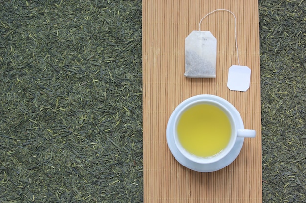 Top view of Tea cup with tea bag on dried tea leaves background