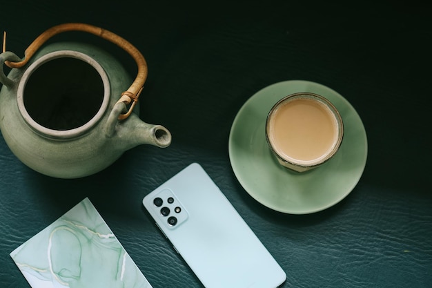 Top view of teapot and glass of milk tea and smartphone. Traditional English breakfast black tea wit