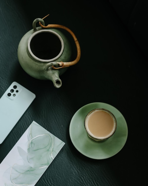 Top view of teapot and glass of milk tea and smartphone. Traditional English breakfast black tea wit