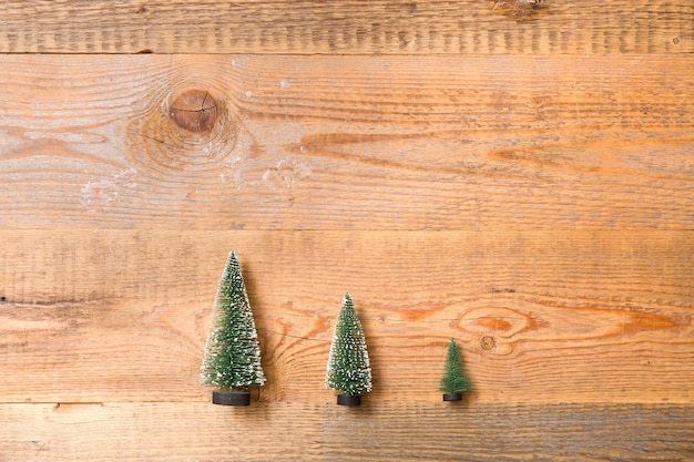 Top view on three little Christmas trees on wooden background Holidays and winter concept