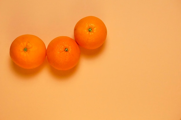 Top view of three oranges on patel orange background. flat lay