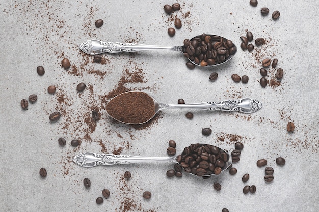 Top view of three spoons with coffee and coffee beans on light background. Flat lay composition.